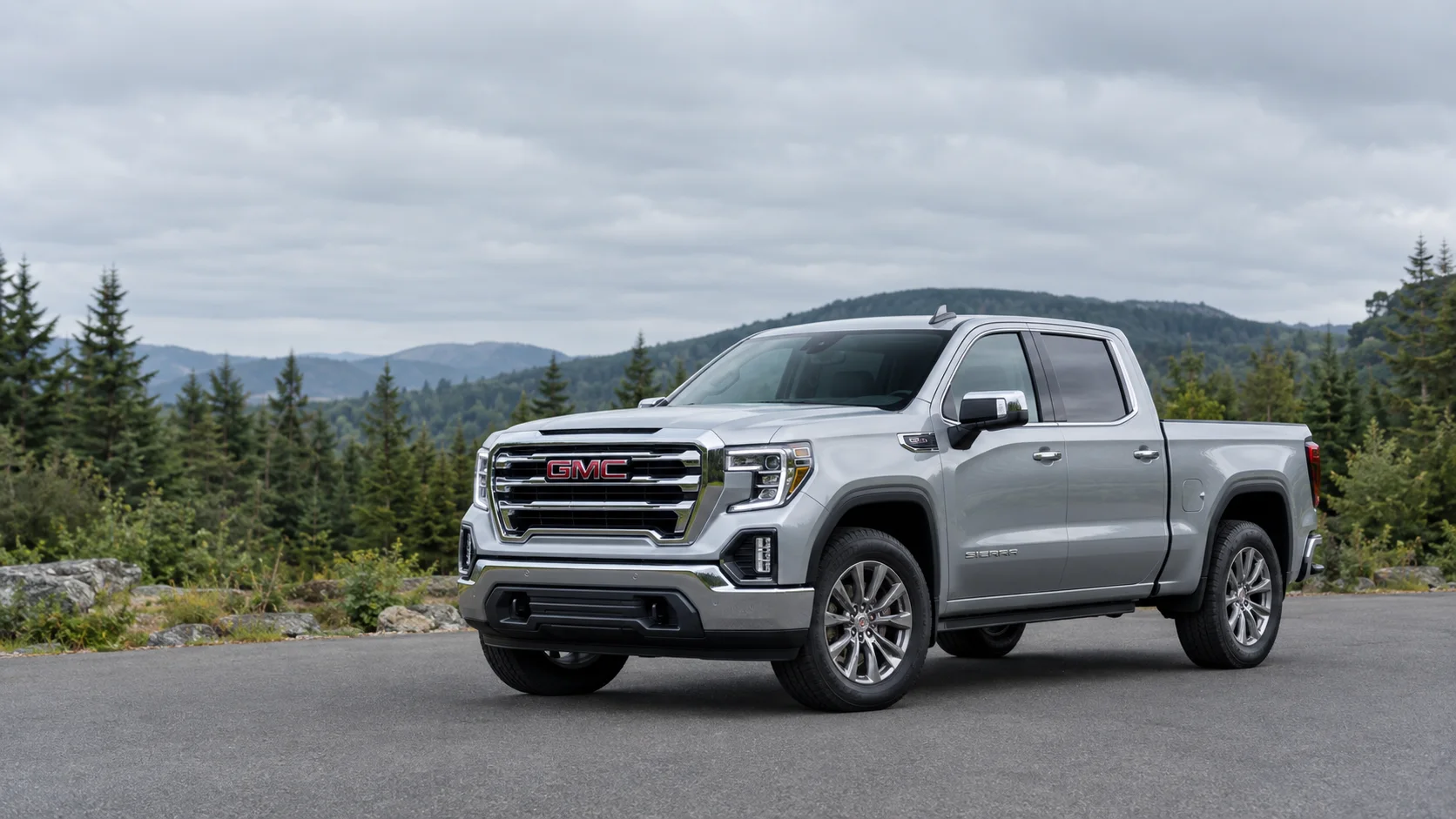 Silver GMC Sierra pickup truck on a wooded road